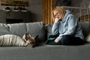 Cão triste deitado no sofá ao lado de sua dona